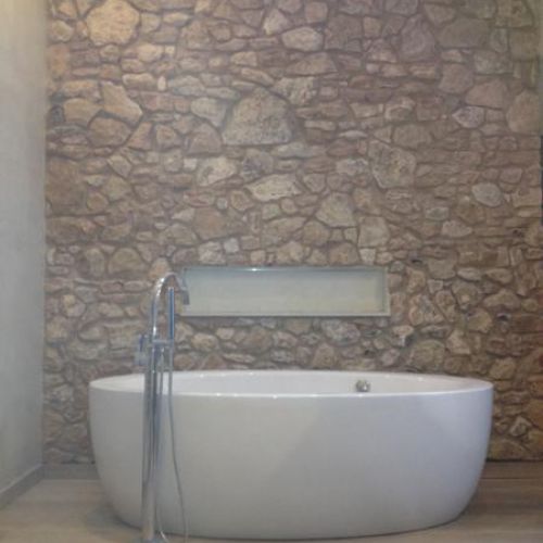 Banyera exempta en bany amb paret de pedra