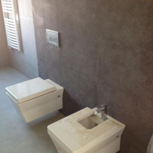 Sanitarios blancos sobre pared en color gris