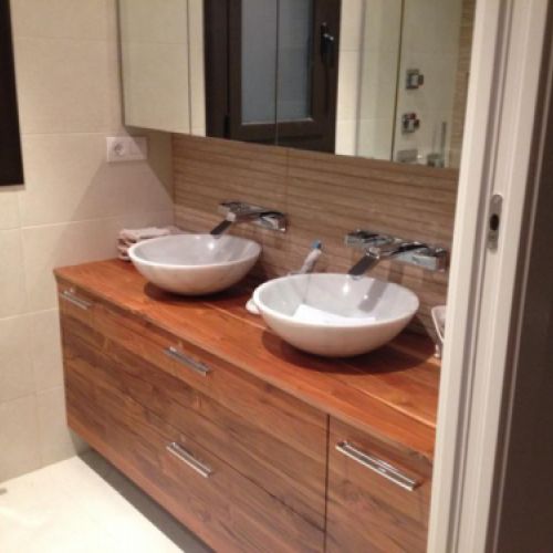 Dos lavabos sobre mueble de madera rojiza y paredes de gres