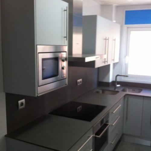 Reforma de cocina con muebles blancos, azul en la pared  y encimera oscura