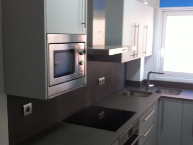 Reforma de cuina amb mobles blancs, blau a la paret i taulell fosc