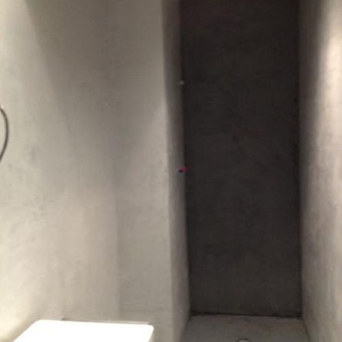 Baño con plato de ducha con pared de microcmento