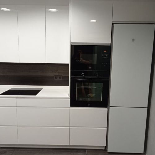 Cuina amb mobles de color blanc i frontal de paret negre
