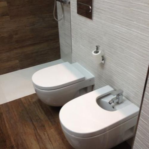 Sanitarios sobre pared en baldosa blanca y plato de ducha