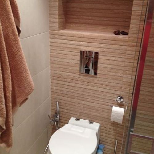 Baño con sanitario sobre pared de gres en láminas y pared lateral con baldosa cuadrada