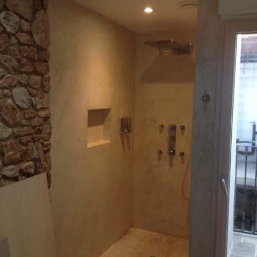 Baño con pared de piedra y microcemento